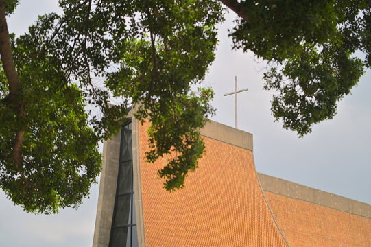 Cross atop iconic Luce Chapel featuring parabolic curved walls with yellow diamond-shaped glazed tiles, representing modernist architecture masterpiece in Taiwan.