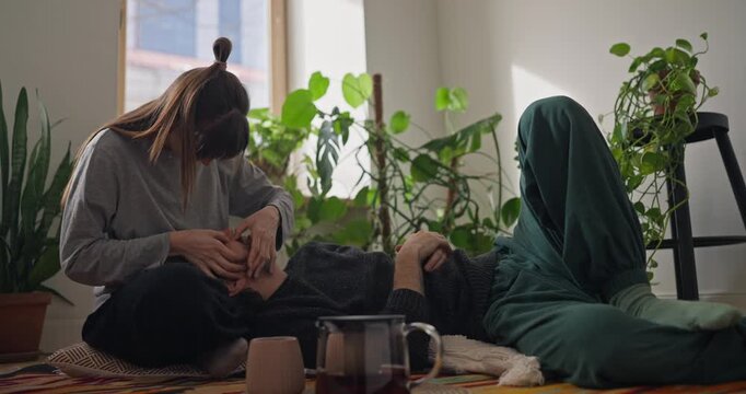 Girl pops her boyfriend pimples when he tries to rest and lies on her lap during a cozy tea party at home with house plants