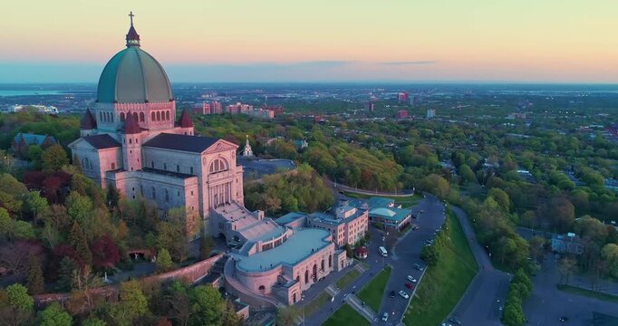 Aerial view of Saint Joseph's Oratory of Mount Royal in Montreal, Canada. People visit the basilica for prayer and pilgrimage. The building is surrounded by trees.