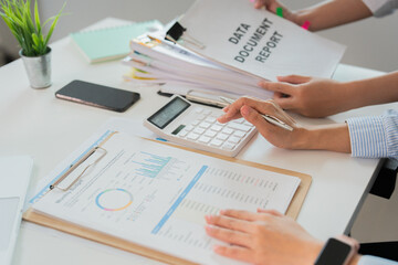 Data Analysis in Office. Woman reviewing documents and calculator for report preparation.