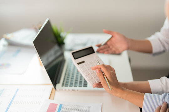 Financial Analysis. Two women calculating figures with a calculator and laptop in an office.