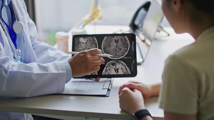 Doctor and patient in hospital. doctor explaining the results of skull x-ray. patient looking at skull x ray on tablet while doctor explaining the result. - Powered by Adobe