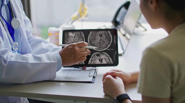 Doctor and patient in hospital. doctor explaining the results of skull x-ray. patient looking at skull x ray on tablet while doctor explaining the result. - Powered by Adobe