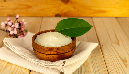 Fototapeta premium Wooden bowl with creamy delight : A rustic wooden bowl filled with a velvety smooth cream creation. It's accented with an elegant green leaf, resting gently atop a delicate napkin