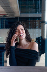 Happy young woman laughing while talking on mobile phone outdoors