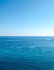 Obraz premium A stunning view of the sparkling ocean from a modern apartment balcony, featuring vibrant blue waters, gentle waves, and a clear sky dotted with fluffy clouds.