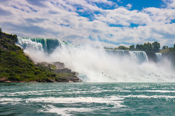 The gushing turquoise water from the Niagara falls with blue sky and white clouds the beautify scenry of nature