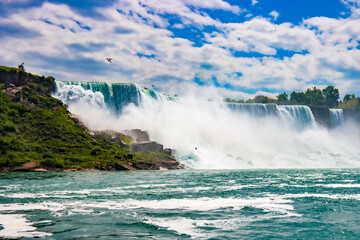 The gushing turquoise water from the Niagara falls with blue sky and white clouds the beautify scenry of nature