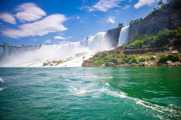 The gushing turquoise water from the Niagara falls with blue sky and white clouds the beautify scenry of nature