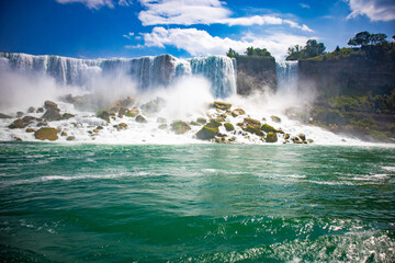 The gushing turquoise water from the Niagara falls with blue sky and white clouds the beautify scenry of nature
