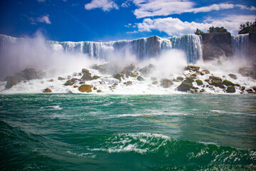 The gushing turquoise water from the Niagara falls with blue sky and white clouds the beautify scenry of nature