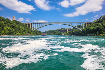The gushing turquoise water from the Niagara falls with blue sky and white clouds the beautify scenry of nature