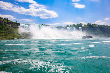The gushing turquoise water from the Niagara falls with blue sky and white clouds the beautify scenry of nature