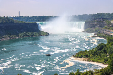 The gushing turquoise water from the Niagara falls from the Canada side with blue sky and white clouds the beautify scenry of nature