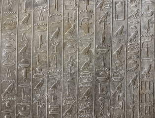Ancient Egyptian hieroglyphic carvings engraved on a stone wall.
