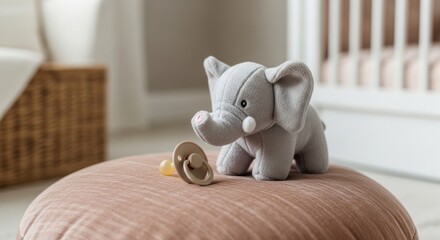 Adorable plush elephant toy and pacifier on a soft cushion in a cozy nursery setting