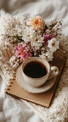 Cozy morning scene coffee cup on a book, nestled in a knit sweater, with a bouquet of delicate flowers