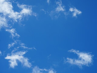 A vivid blue sky framed by thin, wispy white clouds forming a natural “cloud ring.” The clouds create an open window-like space in the center, giving the impression of a framed view of the sky.