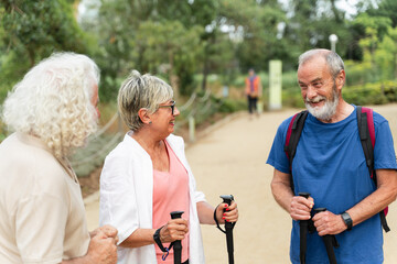 Group of senior friends talking after doing fitness trekking exercise walking in the park