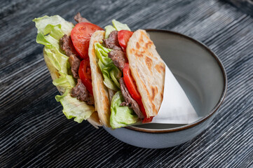Homemade flatbread with beef and tomatoes on a table in a cafe. 