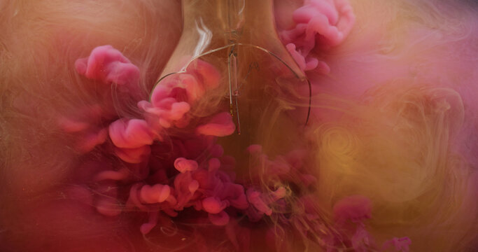 Broken light bulb. Vapor paint. Defocused orange pink color fluid splash smoke cloud filling cracked glass in water on abstract background. - Powered by Adobe