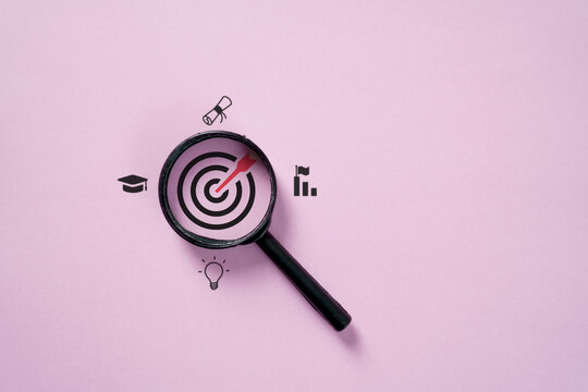 Magnifying glass focusing on target with education icons, symbolizing learning goals, knowledge, career achievement, academic success, innovation, and personal growth.