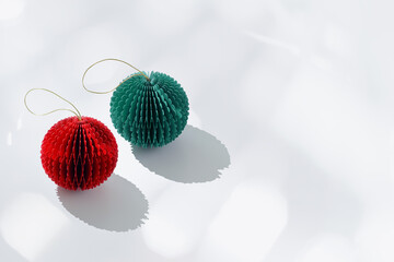 Green and red paper Christmas ornaments shaped round balls on light blue background bokeh and...