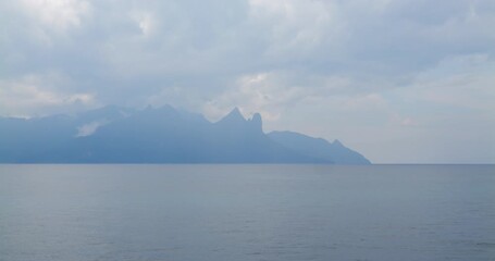 Characteristic view of Tioman Island rises from South China Sea, its peaks shrouded in mist under cloudy sky, creating serene and captivating view. Looking to destination place from passenger ferry