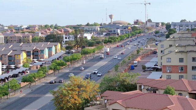 Aerial 4K footage of cars moving on a road between apartment blocks in Midrand, Johannesburg, South Africa. Daylight, clear sky, midday, ideal for metropolitan transitions.