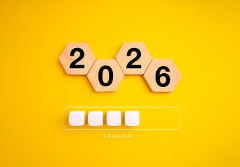 Wooden hexagons show 2026 above loading bar on yellow background, symbolizing upcoming year, new beginning, goal planning, future vision, progress, digital transformation and positive mindset concept.