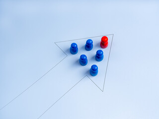 Leadership concept with red figure leading blue team in arrow formation on light background,...
