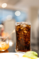 Refreshing Cold Beverage with Ice Cubes in a Transparent Glass Against a Blurred Background