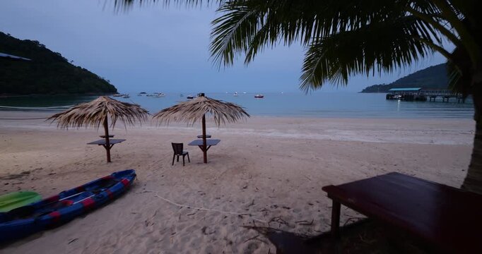 First person view walk from restaurant area to empty Juara Beach at dusk, typical view of Tioman Island but without any people at this time. Camera walk out to sand, revealing tranquil beach scene