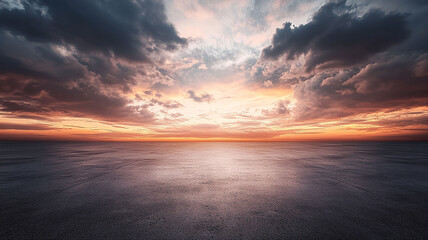 Fototapeta premium A dramatic sky with clouds over a concrete floor. A beautiful sunset over a vast, empty asphalt plain.
