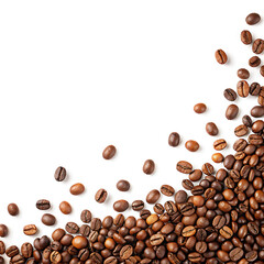 Obraz premium Scattered roasted coffee beans arranged on a white background