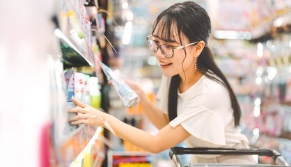 Young adult asian woman customer choosing laundry liquid detergent from household shelf shopping at asia supermarket © dodotone