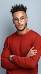Obraz premium Studio portrait of a young man of color with stylish glasses and a trendy hairstyle, confidently posing with crossed arms 