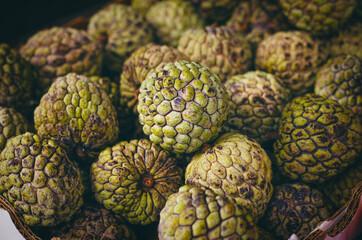 Obraz premium A close-up view highlights the textured surface and natural color variations of several sugar apples. Their greenish skin with brown spots adds an organic, rustic charm. 