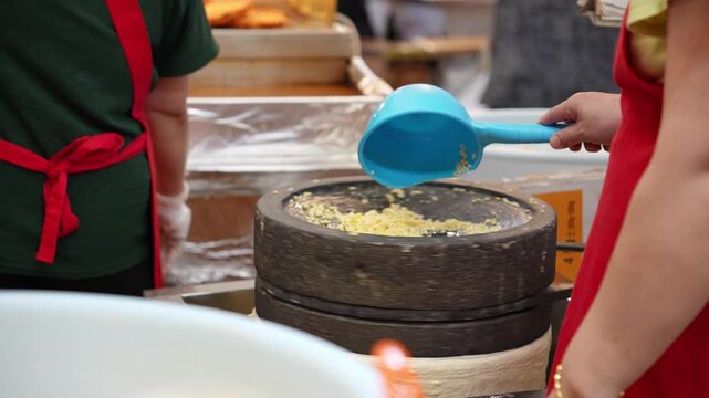 市場の屋台で緑豆を石臼で挽いているシーン
