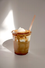 Einsp&auml;nner coffee (Vienna coffee). Coffee topped with cream. Served in a clear disposable cup with a wooden stick.
