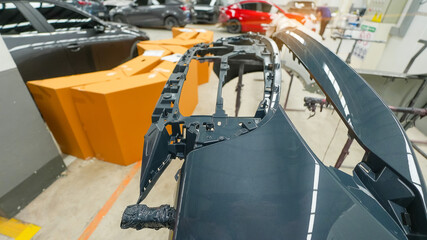 damaged car side skirt undergoing repaint after a heavy collision in an auto body workshop. Insurance repair process showing restoration, sanding, and painting to return the vehicle to its original