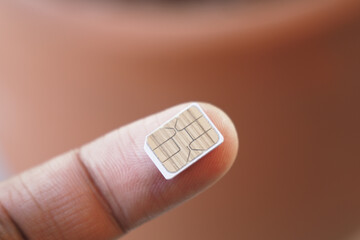 Tiny SIM card held on a finger in close-up view