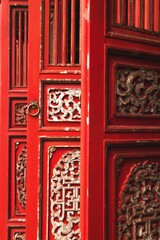 Ornate red wooden door with intricate carvings and a round door handle.