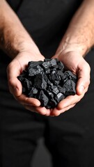 Dark charcoal held in cupped hands