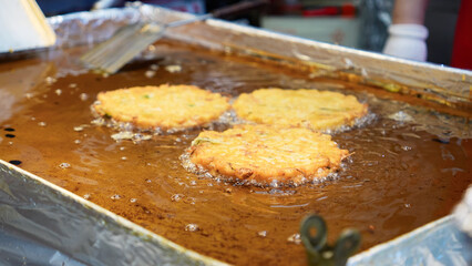 A scene of mung bean pancakes being grilled at a market stall