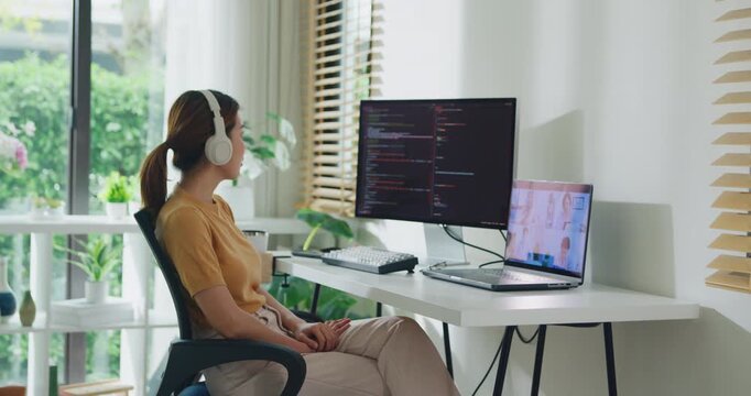 Young Asia female programmer meeting video conference discuss work prompt AI bot IT app program nomad, video game, terminal with coding, user interface, data center on desktop computer at home office.