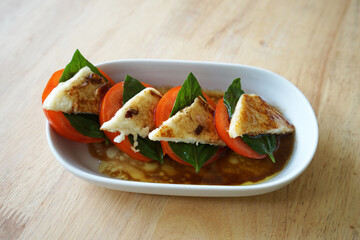Caprese salad- Italian salad made of sliced fresh mozzarella, tomatoes and sweet basil, seasoned with salt, olive oil, arugula and Balsamic vinegar dressing