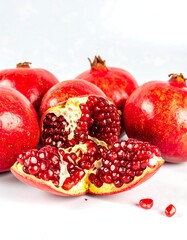 Close-up of several whole pomegranates and a cut one revealing juicy arils