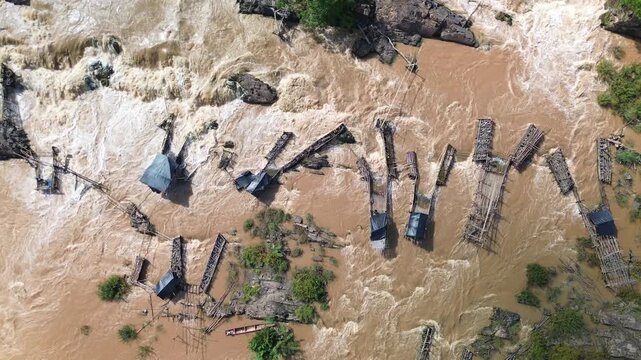 Traditional fish traps along Mekong River near the 4000 islands of Laos, drone aerial top shot overhead flowing water