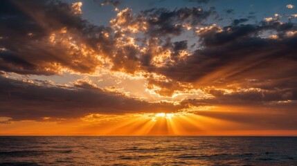 The sky is orange and the sun is setting over the ocean. The clouds are scattered and the water is calm